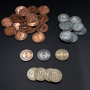 Könnte beinhalten: Eine Sammlung von Metall-Spielmarken in verschiedenen Farben. Kupferfarbene Marken mit der Zahl "1", silberne Marken mit "5" und goldfarbene Marken mit "10". Die Marken sind auf einer dunklen Oberfläche verstreut.
