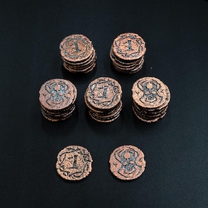 Peut inclure: Pi&egrave;ces de monnaie fantastiques de couleur cuivre avec une finition vieillie. Chaque pi&egrave;ce porte le chiffre "1" et un cr&acirc;ne ou un motif orn&eacute;. Plusieurs piles et pi&egrave;ces individuelles sont dispos&eacute;es sur une surface sombre, pour jeux de table ou collection.