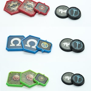 May include: Set of three different sized, hexagonal, printed game tokens. The tokens are yellow, red, blue, and green. The tokens have different symbols and designs.  The set also includes four black plastic rings of different sizes.  The text "SET 2" is printed on a white background.