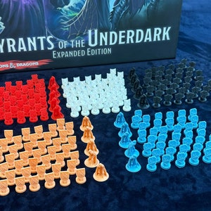 Peut inclure: Un ensemble de pions de jeu en plastique de différentes couleurs, dont le rouge, le blanc, le noir, l'orange et le bleu. Les pions sont disposés en grille sur une surface bleue. Les pions de jeu sont pour le jeu de rôle Dungeons & Dragons "Tyrants of the Underdark: Expanded Edition".