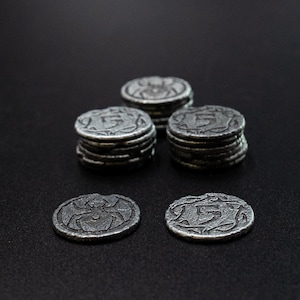 Peut inclure: Collection de pi&egrave;ces de monnaie en m&eacute;tal de style antique. Certaines pi&egrave;ces sont empil&eacute;es, tandis que d'autres sont affich&eacute;es individuellement. Les pi&egrave;ces pr&eacute;sentent une araign&eacute;e ou le chiffre "5". Les pi&egrave;ces ont un aspect vieilli.