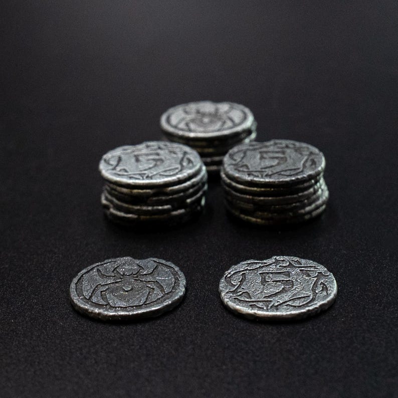 Peut inclure: Collection de pi&egrave;ces de monnaie en m&eacute;tal de style antique. Certaines pi&egrave;ces sont empil&eacute;es, tandis que d'autres sont affich&eacute;es individuellement. Les pi&egrave;ces pr&eacute;sentent une araign&eacute;e ou le chiffre "5". Les pi&egrave;ces ont un aspect vieilli.