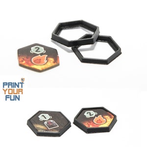 Könnte beinhalten: Zwei schwarze sechseckige Spielmarkenhalter und zwei Spielmarken mit einem Feuerdesign und den Zahlen 1 und 2. Die Spielmarken befinden sich auf einer weißen Oberfläche.