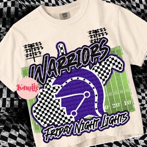 May include: A white t-shirt with a graphic design featuring a purple helmet, a chequered pattern, and the text "WARRIORS" and "FRIDAY NIGHT LIGHTS".