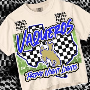May include: A beige t-shirt with a blue and white checkered design, a blue and white graphic of a cowboy riding a horse, and the text "VAQUEROS FRIDAY NIGHT LIGHTS".