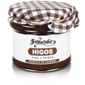 Può includere: Un barattolo di confettura di fichi con un'etichetta bianca con la scritta "Bernardo's HIGOS" in marrone. Il barattolo è sormontato da un coperchio in tessuto a scacchi marrone e bianco. L'etichetta include anche "FICHI / FEIGEN" e "PRODUCTO DE CANARIAS."