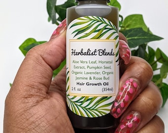 May include: A clear glass bottle with a black cap and a white label that reads "Herbalist Blends Hair Growth Oil 2 fl. oz (354ml)". The label has a green tropical leaf design. The bottle is being held by a hand with pink and red nail polish.