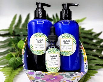 May include: A gift basket filled with blue bottles of Herbalist Blends hair growth shampoo and conditioner, and a small bottle of Herbalist Blends Shay's Hair Growth Oil. The basket is lined with a floral pattern.