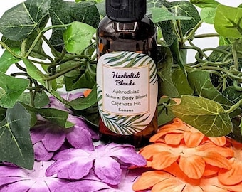 May include: A brown glass bottle with a black cap and a white label that reads "Herbalist Blends Aphrodisiac Natural Body Blend Captivate His Senses". The bottle is surrounded by green leaves and purple and orange flower petals.
