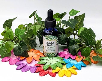 May include: A blue glass bottle with a dropper top containing Herbalist Blends Men's Hair Growth Oil, Shay's Blend, 1 oz (29 ml). The bottle is surrounded by green leaves and colorful flower petals.