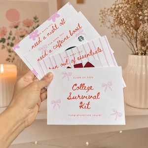 Może przedstawiać: Ręka trzymająca stos białych kart z różowym tekstem i ilustracjami kokardek. Na górnej karcie widnieje napis "College Survival Kit" z "Class of 2026" i "Congratulations Laura!". Inne karty zawierają frazy takie jak "need a night off".