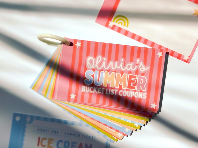 May include: A set of rectangular paper coupons held together by a white plastic ring. The top card features pink vertical stripes, white stars, and the text Olivia's SUMMER BUCKET LIST COUPONS. Additional cards in blue, yellow, and orange are visible.