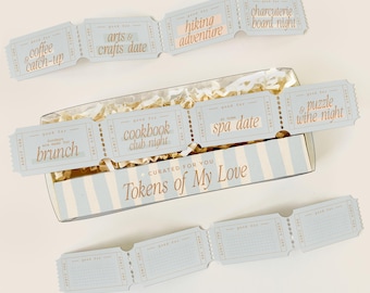 May include: A rectangular box with light blue and white stripes containing shredded paper and a strip of tickets labeled Tokens of My Love. The tickets feature text including coffee and catch-up, arts and crafts date, hiking adventure, charcuterie board night, brunch, cookbook club night, spa date, and puzzle and wine night.