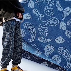 May include: A pair of blue jeans with a paisley pattern. The jeans are made of denim and have a relaxed fit.