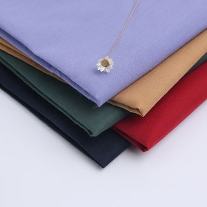 May include: A stack of five fabric swatches in different colors: light purple, brown, dark green, navy blue, and red.