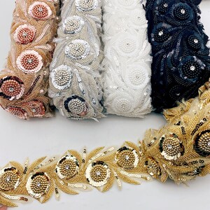 Op de afbeelding: Assortiment van parelversiering met pailletten en strass in goud, zilver, wit, zwart en rosé goud. De versiering heeft een bloemmotief met bladeren en ronde versieringen.