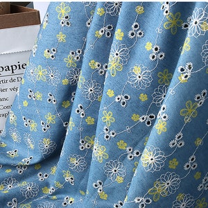 May include: Blue fabric with a white floral pattern and yellow accents. The fabric is folded in half.