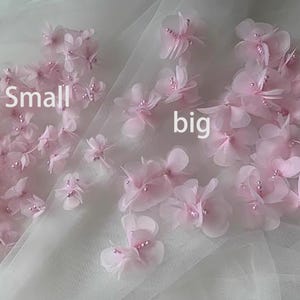 May include: Pink fabric flowers with pearl accents, labeled "small" and "big" on a white tulle background.