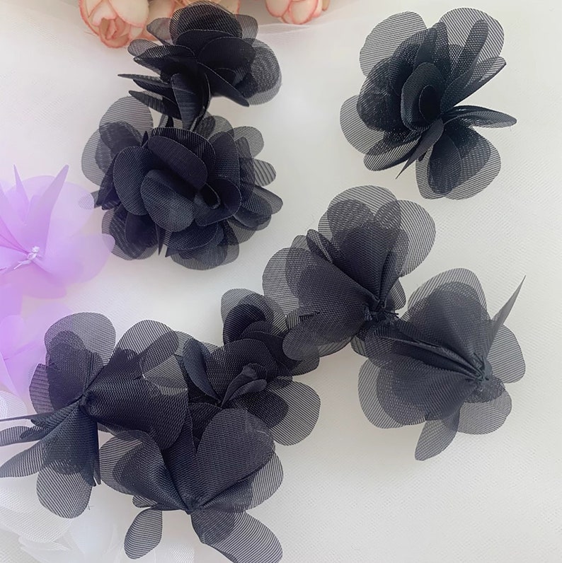 May include: Black mesh fabric flowers, with multiple layers of petals, for sewing or crafting projects.