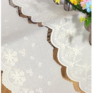 Pode incluir: Bordado de renda de algodão branco com borda festonada e bordado floral. A renda tem um visual delicado e vintage e seria perfeita para adicionar um toque de elegância a qualquer projeto.