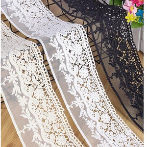 Pode incluir: Três rolos de renda branca e preta com um design floral. A renda é delicada e intrincada.