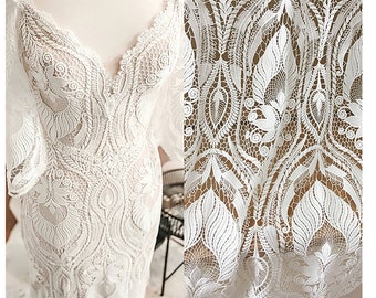 May include: White lace fabric with a delicate floral pattern. The lace is intricate and has a vintage feel.