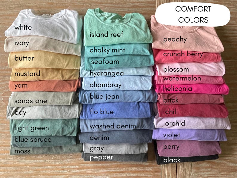K&ouml;nnte beinhalten: Eine Sammlung von T-Shirts in verschiedenen Farben, in drei Spalten gestapelt. Die Farben sind mit Namen wie "wei&szlig;", "Elfenbein", "Butter", "Senf", "Yamswurzel", "Sandstein", "Bucht", "Hellgr&uuml;n", "Blautanne", "Moos", "Inselriff", "kreidige Minze", "Meerschaum", "Hortensie", "Chambray", "Jeansblau", "Flo-Blau", "gewaschenes Denim", "Denim", "Grau", "Pfeffer", "Pfirsich", "Knackbeere", "Bl&uuml;te", "Wassermelone", "Heliconia", "Ziegel", "Chili", "Orchidee", "Violett", "Beere" und "Schwarz" beschriftet.