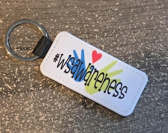May include: White rectangular keychain with the text "#WSAwareness" in black, with blue and yellow handprints and a red heart. The keychain has a silver ring and a black strap.