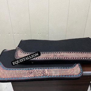 May include: Two black saddle pads with brown leather trim and turquoise stitching. The pads have a woven pattern and floral design.
