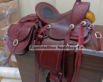May include: A burgundy leather saddle with intricate stitching and a woven pattern. The saddle has two saddlebags with buckles and a stirrup. The saddle is labeled "Equistallion Saddlery Co."