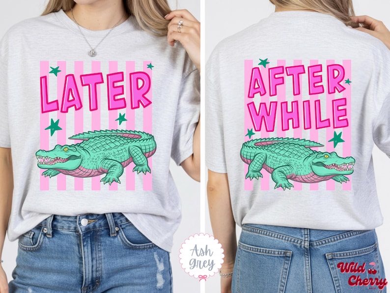 K&ouml;nnte beinhalten: Hellgraues T-Shirt mit rosa und wei&szlig;en Streifen. Auf der Vorderseite steht das Wort &bdquo;LATER&ldquo; in Rosa, ein gr&uuml;nes Alligator und gr&uuml;ne Sterne. Auf der R&uuml;ckseite steht &bdquo;AFTER WHILE&ldquo; und ein gr&uuml;nes Alligator. Ein lustiges, l&auml;ssiges Oberteil.