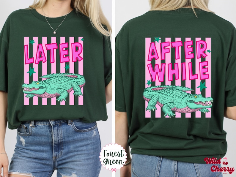 K&ouml;nnte beinhalten: Forstgr&uuml;nes T-Shirt mit einem rosa und wei&szlig; gestreiften Rechteck-Design. Auf der Vorderseite des Shirts steht "LATER" in rosa Buchstaben &uuml;ber einem t&uuml;rkisfarbenen Alligator. Auf der R&uuml;ckseite steht "AFTER WHILE" &uuml;ber einem t&uuml;rkisfarbenen Alligator.