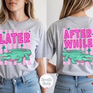 K&ouml;nnte beinhalten: Hellgraues T-Shirt mit rosa-wei&szlig;em Streifendesign. Auf der Vorderseite des Shirts steht das Wort "LATER" und ein gr&uuml;nes Alligator. Auf der R&uuml;ckseite des Shirts steht "AFTER WHILE" mit dem gleichen Alligatordesign.