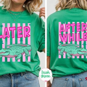 K&ouml;nnte beinhalten: Irisch-gr&uuml;nes T-Shirt mit rosa und wei&szlig;en Streifen. Auf der Vorderseite des Shirts steht das Wort "LATER" &uuml;ber einer Illustration eines tealfarbenen Alligators. Auf der R&uuml;ckseite des Shirts stehen die Worte "AFTER WHILE" &uuml;ber derselben Illustration.