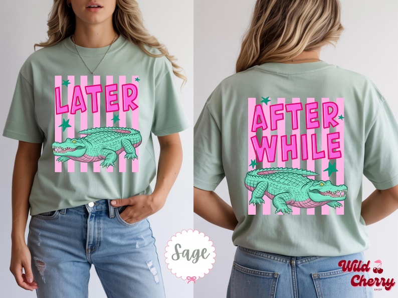 K&ouml;nnte beinhalten: Salbeigr&uuml;nes T-Shirt mit einem gr&uuml;nen Alligator-Design, rosa Streifen und dem Wort "LATER" in Pink. Auf der R&uuml;ckseite steht "AFTER WHILE" und ein passendes Alligator-Design. Ein l&auml;ssiger, bequemer Stil.