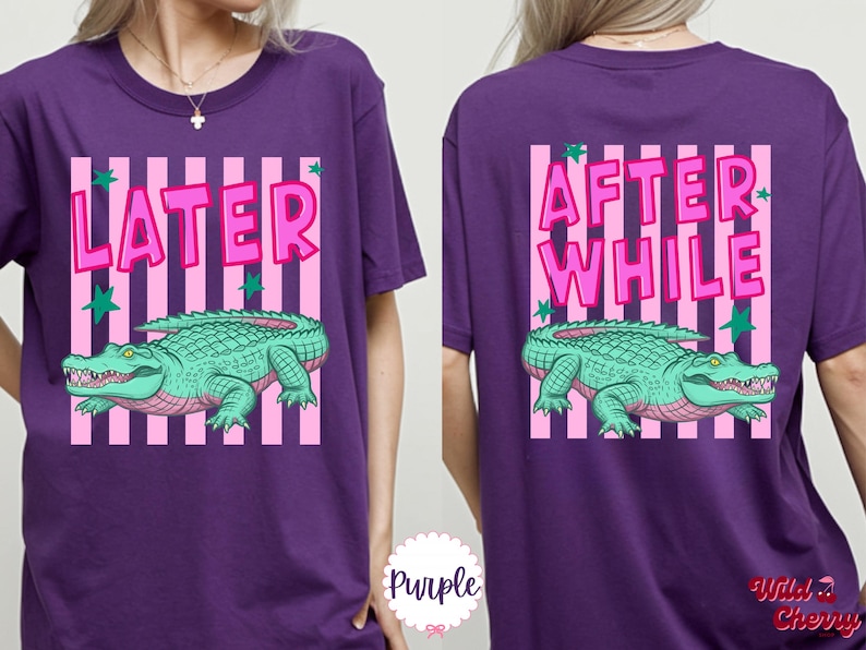 K&ouml;nnte beinhalten: Lila T-Shirt mit einem vorderen Aufdruck &bdquo;LATER&ldquo; und einem hinteren Aufdruck &bdquo;AFTER WHILE&ldquo;. Beide Grafiken zeigen ein gr&uuml;nes Alligator &uuml;ber rosa und wei&szlig;en Streifen, mit gr&uuml;nen Sternen.