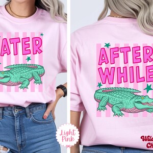 K&ouml;nnte beinhalten: Hellrosa T-Shirt mit einem Cartoon-Alligator-Design. Auf der Vorderseite des Shirts steht "LATER" in rosa Buchstaben mit einem gr&uuml;nen Alligator darunter. Auf der R&uuml;ckseite steht "AFTER WHILE" mit einem passenden Alligator.