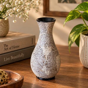 May include: A decorative vase with a narrow neck and a bulbous base, featuring a white and grey crackle glaze finish. The rim and the base of the vase are finished in a solid black colour, providing a contrast to the textured, web-like pattern.