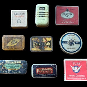 May include: A selection of antique tins and boxes, including tobacco and medicinal products. Featured items include "Craven A" cigarettes, "Life Guard" tobacco, and "Throat Pastilles". The items are in various shapes and colors, with text and graphics.