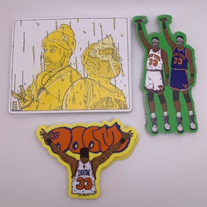 Puede incluir: Tres pegatinas de vinilo amarillo y naranja con una ilustración de dibujos animados de un jugador de baloncesto que lleva una camiseta con el número 33 y el texto "DOOM". El jugador está sosteniendo un balón de baloncesto y está rodeado del texto "MF DOOM".
