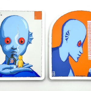 May include: Two art prints featuring a blue-skinned humanoid with red eyes. One print shows the humanoid holding a yellow figure and a figure wearing a basketball jersey. The other print has an orange background and the humanoid holding a small red box.