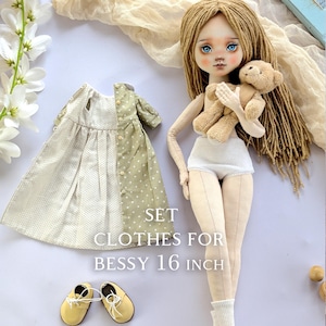 May include: A set of clothes for a 16 inch doll, including a green and white polka dot dress, a pair of yellow shoes, and white socks. The text "SET CLOTHES FOR BESSY 16 INCH" is printed on the white background.
