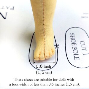May include: A doll's foot made of light yellow fabric, with a measurement of 0.6 inches (1.5 cm) indicated. The text states the shoes are suitable for dolls with a foot width of less than 0.6 inches (1.5 cm).
