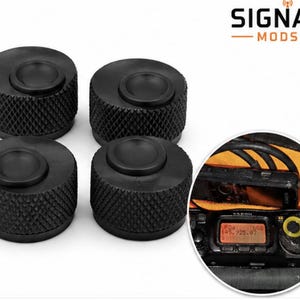 Puede incluir: Cuatro perillas cilíndricas negras con un agarre texturizado de patrón de diamante y una superficie superior lisa y cóncava. Un recuadro circular muestra un radio con una perilla similar instalada, con pantalla digital naranja y el texto SIGNAL MODS.