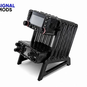 Puede incluir: Equipo de radio negro montado en un soporte negro con un diseño único. El soporte tiene líneas verticales y una base estable. Las unidades de radio tienen botones, perillas y pantallas. El texto "SIGNAL MODS" es visible en la esquina superior izquierda.