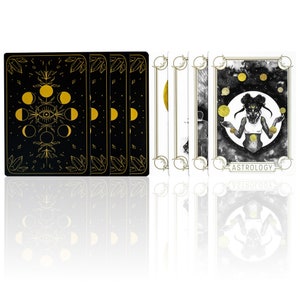 Card backs show the moon phases, an evil eye and crystals in gold over a black background. The oracle card deck front shows a woman of color, black girl juggling planets in her hands. She is a planetary witch and looks like the Black Sailor Moon