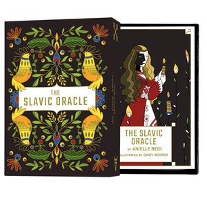 The Slavic Oracle deck set box is open showing the colorful and floral box front and the guidebook cover with a young woman holding a gromnica (a beeswax candle) which lights up half of her face.
