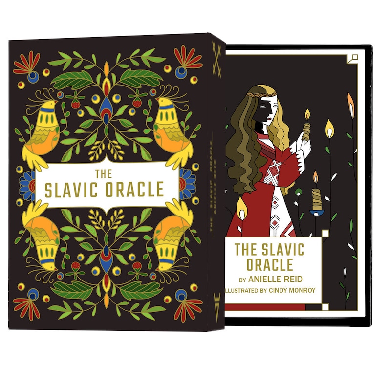 The Slavic Oracle deck set box is open showing the colorful and floral box front and the guidebook cover with a young woman holding a gromnica (a beeswax candle) which lights up half of her face.