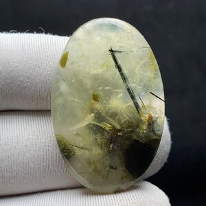 Naturlig prehnitcabochon | 35,4x22,5x5,1 MM 39,00 karat | Med mjukgrön genomskinlighet med mörka mineralinneslutningar.