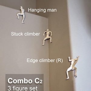 May include: A set of three off-white wall-mounted figures labeled Hanging man, Stuck climber, and Edge climber (R). The text Combo C2 3 figure set as shown is displayed in a gray box. These figures are depicted in various climbing poses.